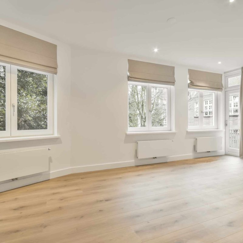 A large room in an empty new house with large windows in a minimalist style, made in white tones